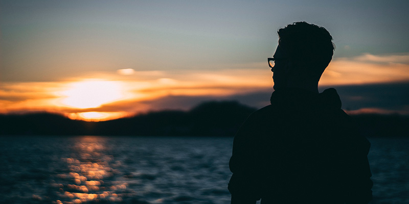 Silhouette of a young man watching the sunset.
