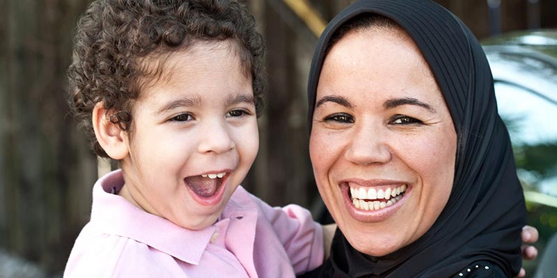 Muslim mother holding her young son, both smiling.