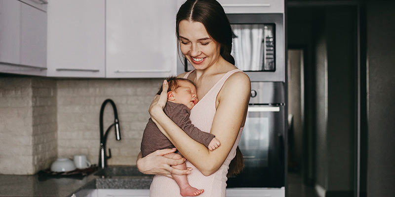 Young mum smiling and holding her newborn child.