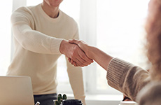 Man and woman shaking hands as they begin a job interview.