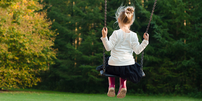 Young girl on a swing, facing away from camera.