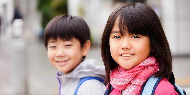 Young Asian brother and sister walking to school together.