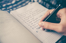 Close up of person writing a checklist on a notepad.
